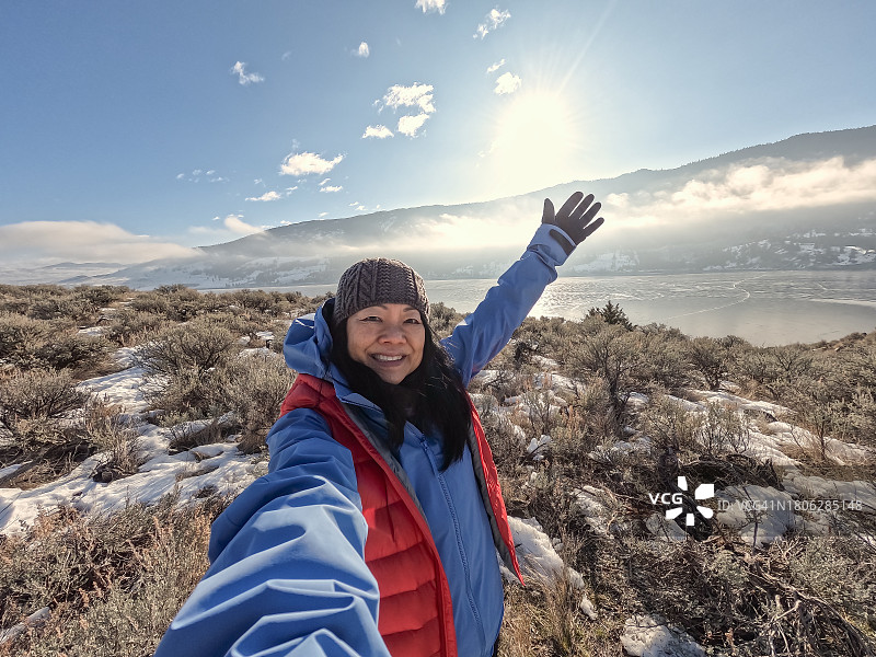 年长的亚洲女性徒步前往冰冻湖泊时自拍图片素材
