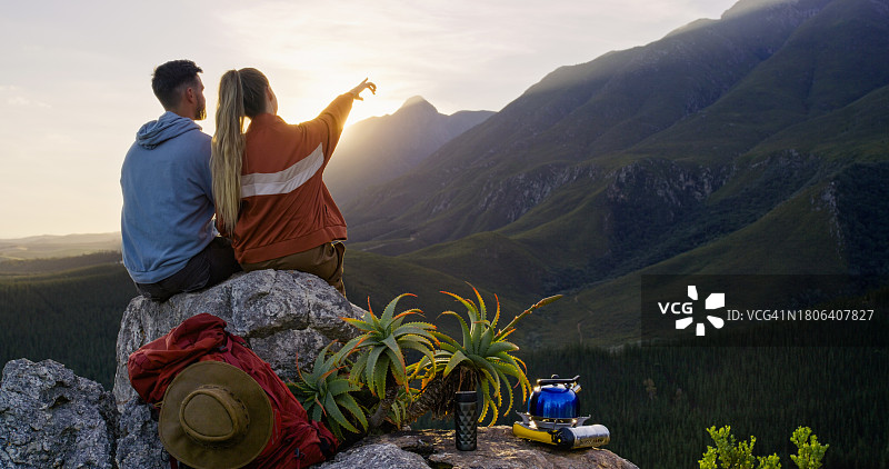 情侣在山顶上指向远方，欣赏日出美景图片素材