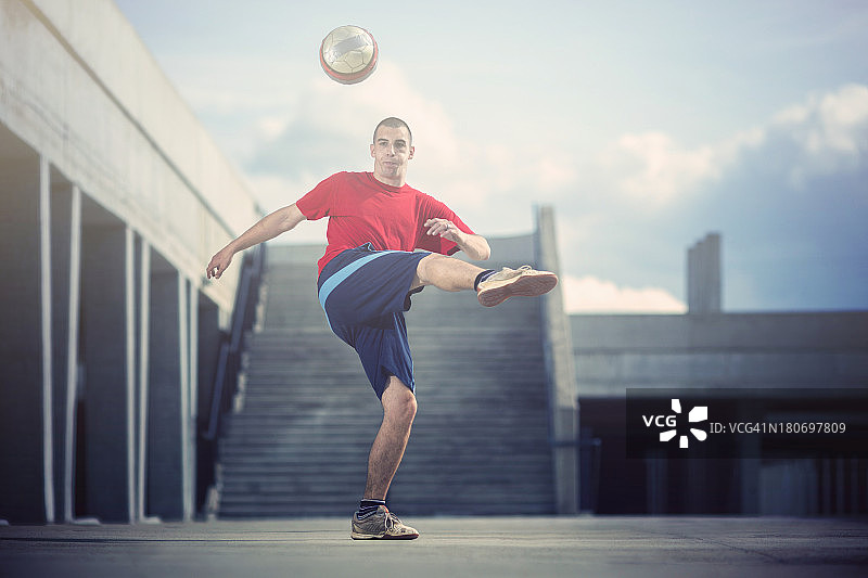 年轻男人在市区踢足球图片素材