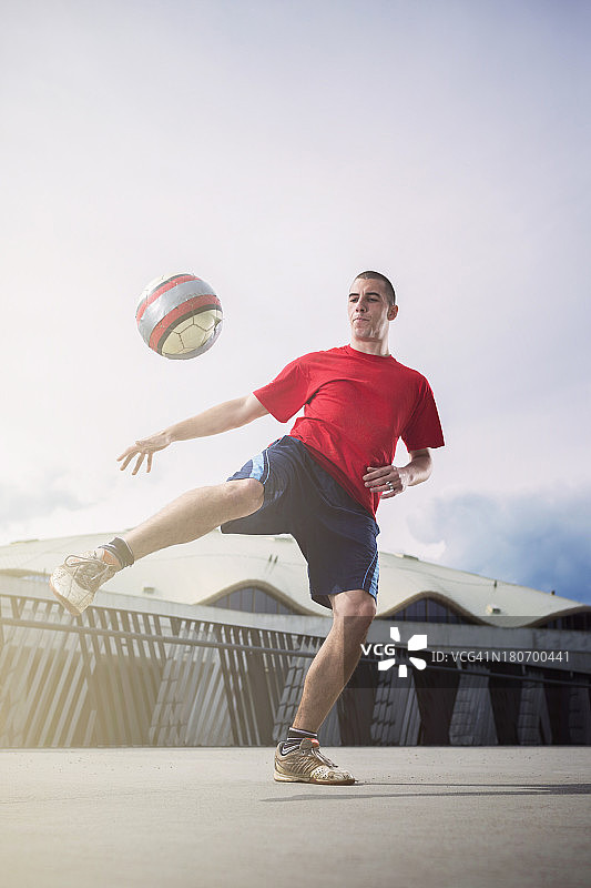 年轻男人在市区踢足球图片素材