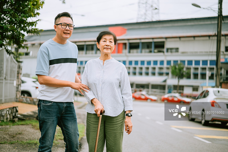 一位亚洲老妇人带着儿子在街上行走图片素材