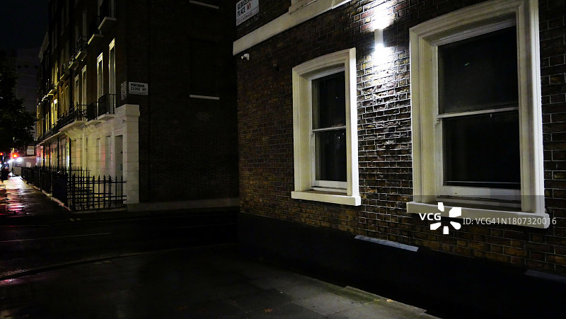 伦敦住宅楼的夜景和侧视图：风化的砖墙和白色窗户图片素材