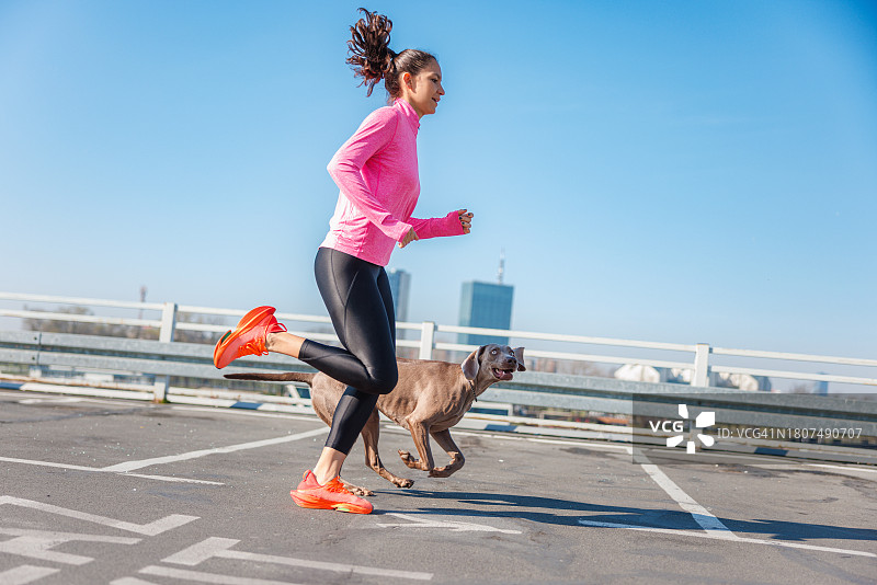 在空旷停车场上跑步的女人和她的狗图片素材