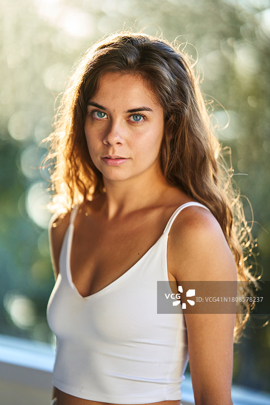 年轻女子，金色长发和蓝色眼睛看着镜头，背景虚化图片素材