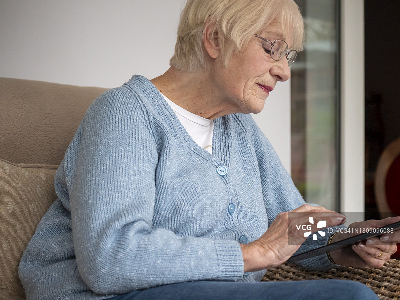 使用平板电脑进行网上购物的80岁女士图片素材
