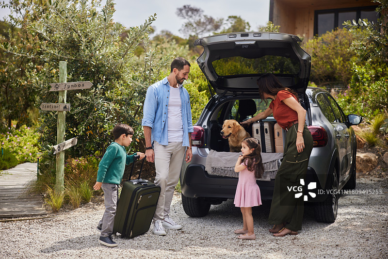 微笑的一家人带着狗在度假住宿卸车图片素材