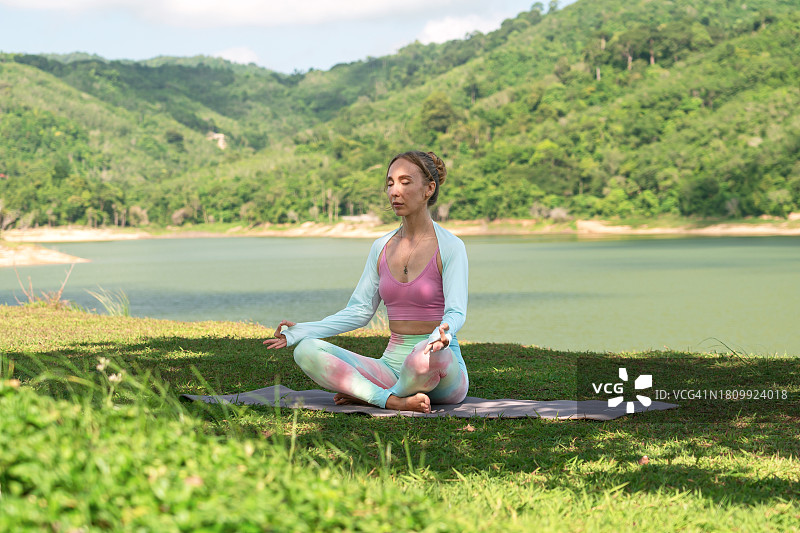 女子在湖边草地上做瑜伽图片素材