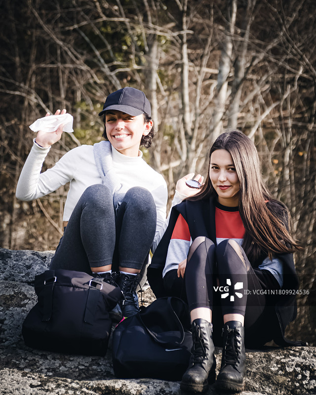 朋友们坐在树旁人行道上的微笑合影图片素材