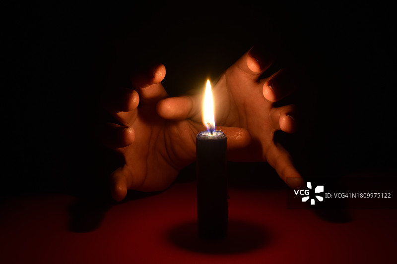 在暗室中手持点燃的蜡烛图片素材