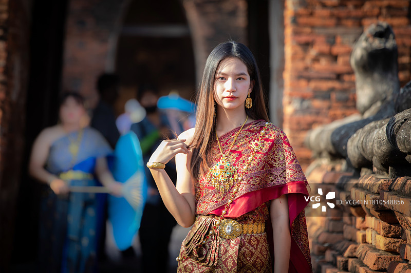 穿着泰国传统服装的漂亮亚洲女人在阿瑜陀耶的柴瓦塔纳兰寺的古老宝塔旁图片素材