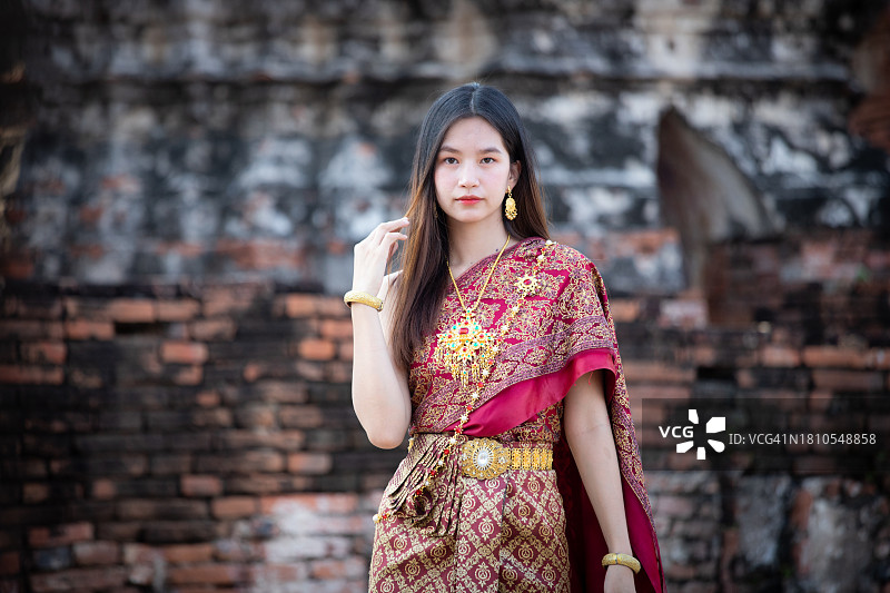 穿着泰国传统服装的漂亮亚洲女人在阿瑜陀耶的柴瓦塔纳兰寺的古老宝塔旁图片素材