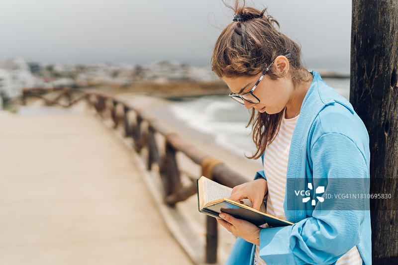 年轻女人在海边读书图片素材