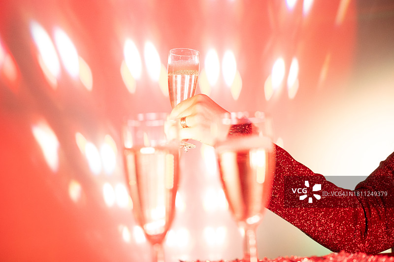 在聚会上，一位女士手持一杯香槟，迪斯科灯光图片素材