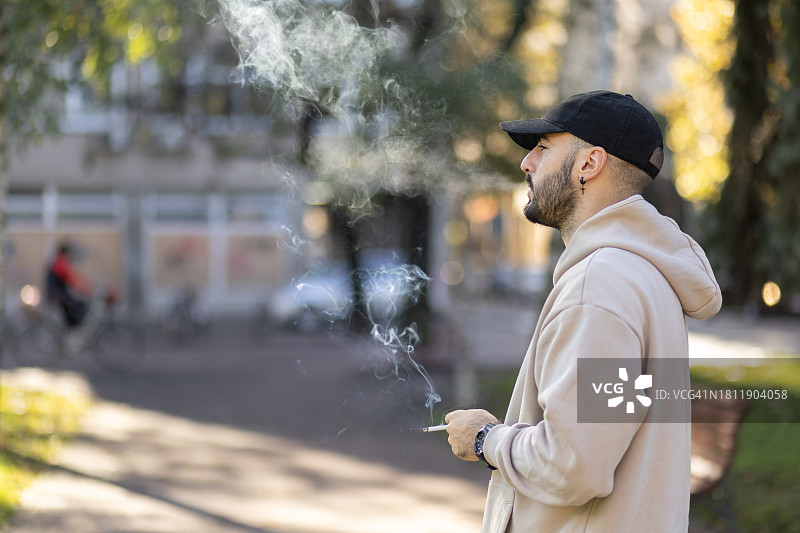 在公园里吸烟的年轻男子图片素材