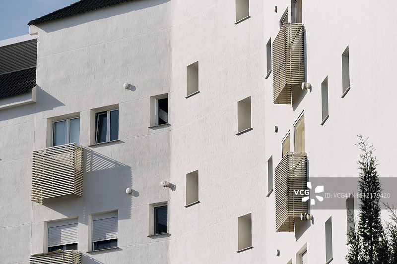 一排建筑外墙的窗户，带有通风口，天空为背景的侧视图图片素材