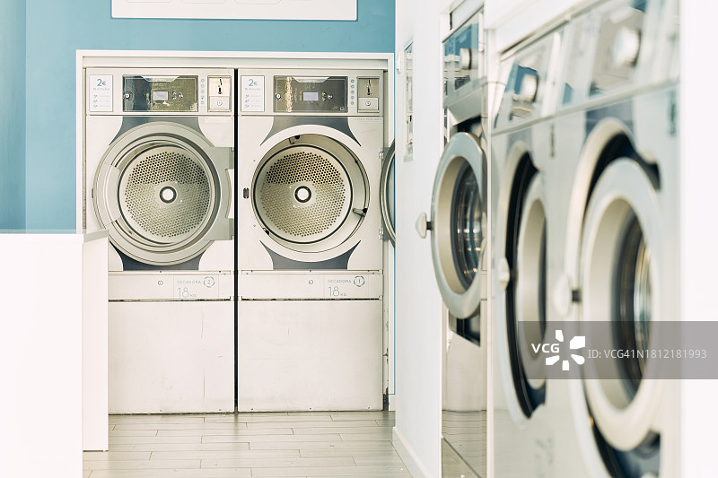 自助洗衣房内一排空的金属烘干机，配有圆形玻璃门图片素材