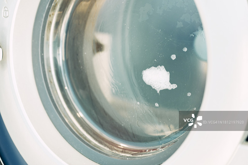 侧视图：洗衣房里正在运行的洗衣机图片素材
