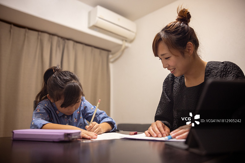 小女孩在餐厅做作业，妈妈在一旁辅导图片素材