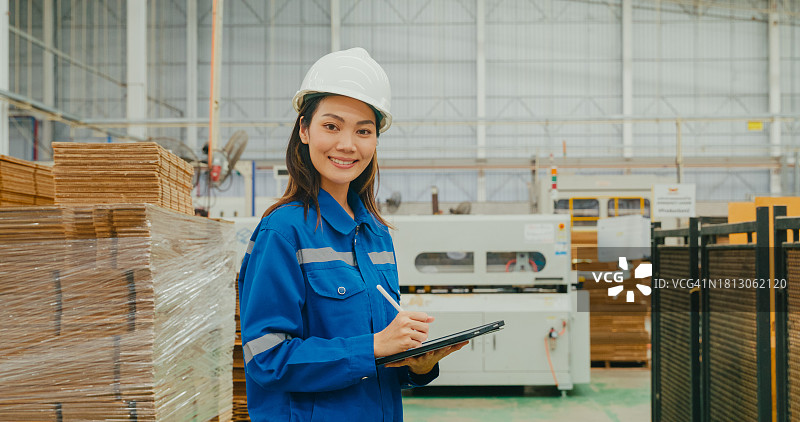 在制造工厂中微笑并看向镜头的亚洲女工业工程师。在制造工厂或生产工厂工作图片素材