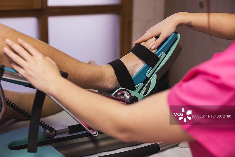 年轻的理疗师为膝盖受伤的病人进行康复治疗图片素材