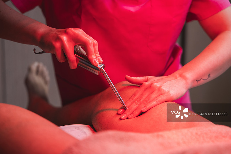 年轻理疗师在理疗中心用热灯对膝盖损伤进行治疗按摩图片素材