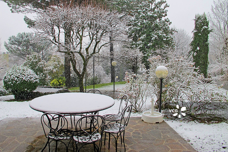 初雪，带桌椅的露台、草地和树木图片素材