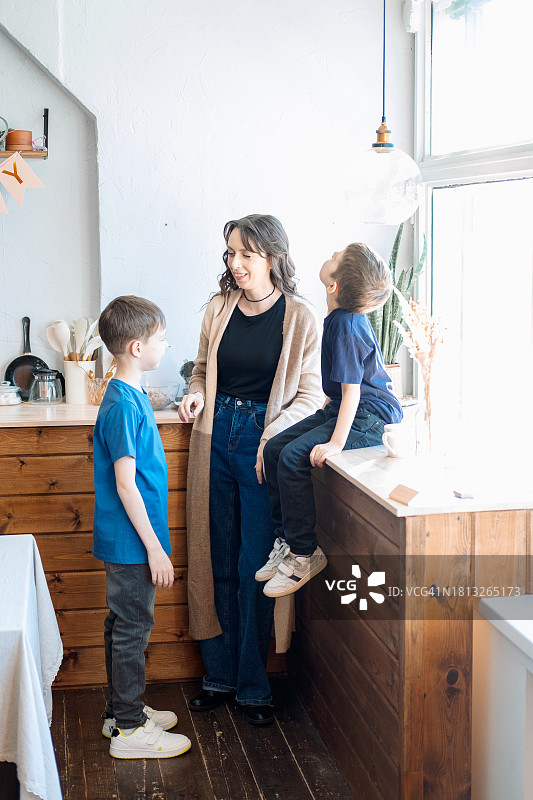 在厨房里，母亲与两个儿子亲密交流图片素材