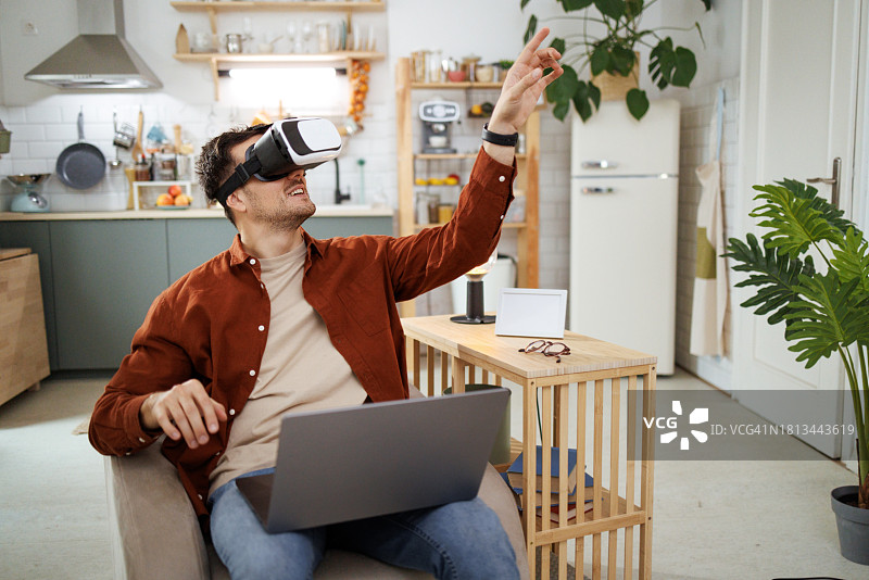 年轻男子在家中扶手椅上使用VR眼镜图片素材