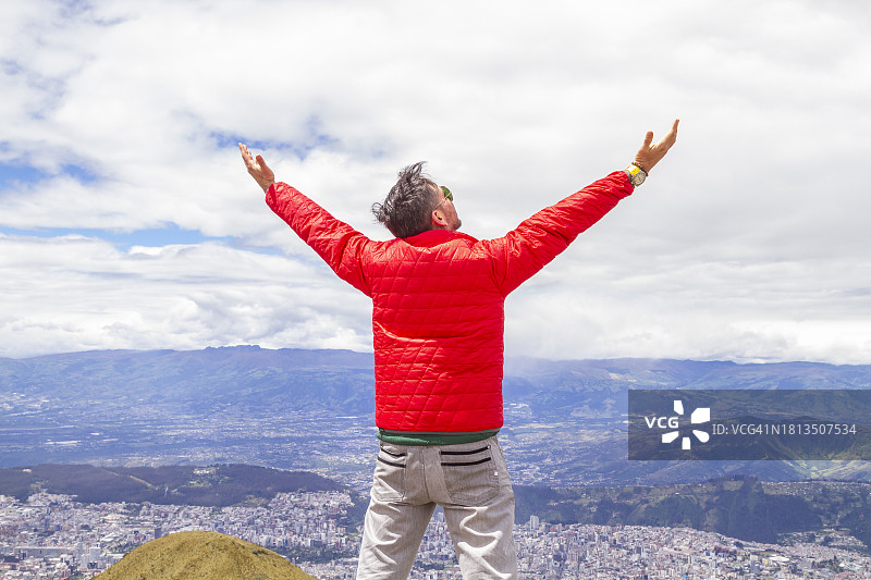 年轻男人独自旅行，在火山顶峰张开双臂的肖像图片素材