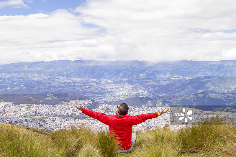 年轻男人独自旅行，在火山顶峰张开双臂的肖像图片素材