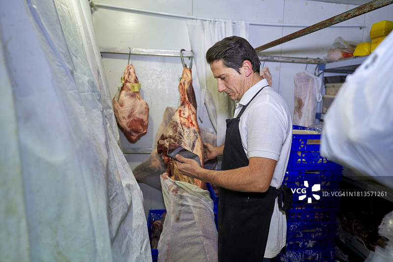 西班牙肉店的肉贩使用平板电脑管理库存和保质期图片素材