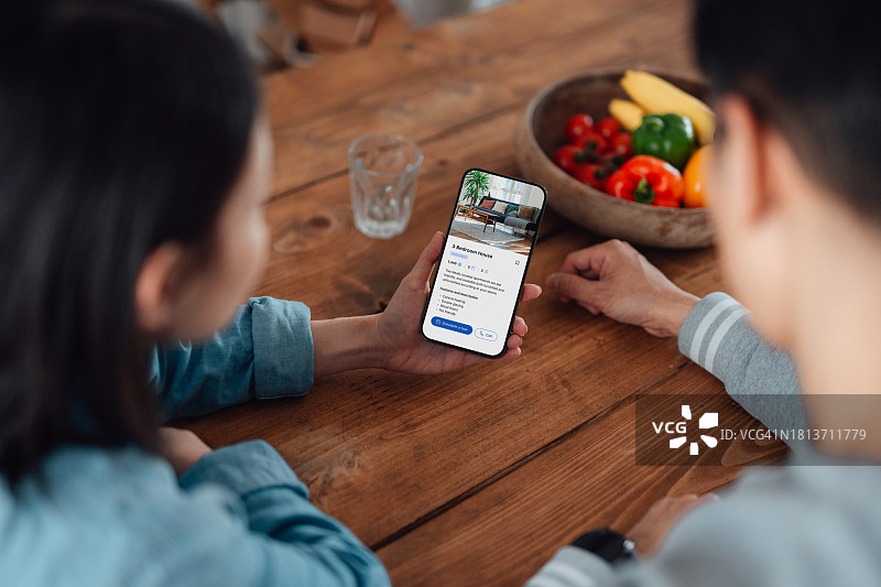 年轻夫妇通过手机App查看房产信息图片素材