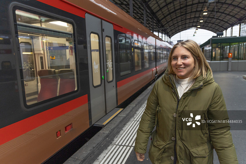 女子走上站台，一列火车停靠在旁图片素材