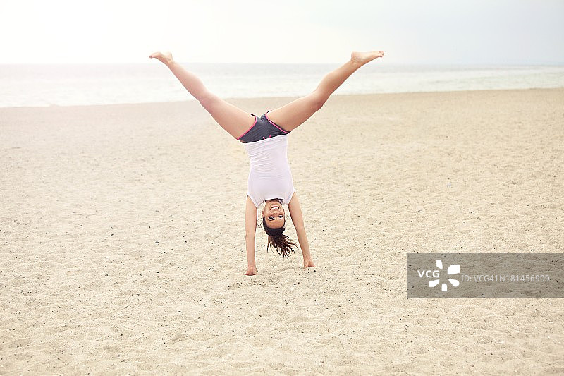 在海滩上倒立的快乐女人图片素材
