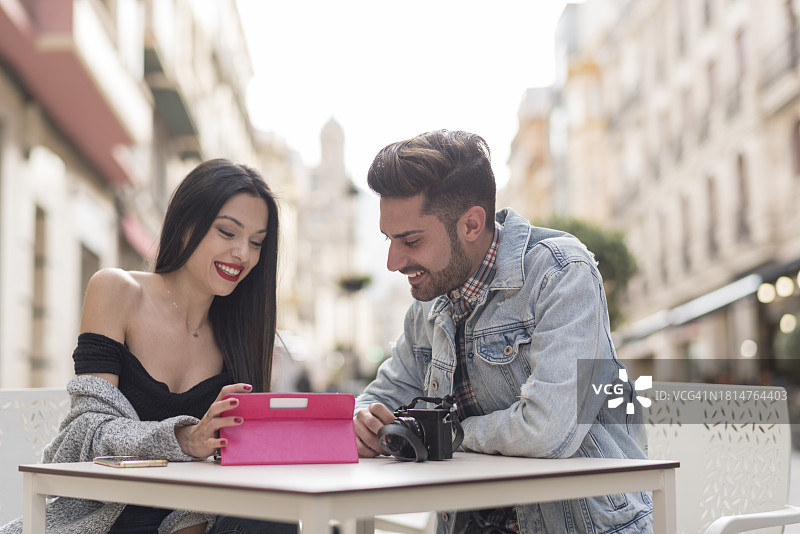 年轻情侣在城市户外酒吧露台用平板电脑查看照片图片素材