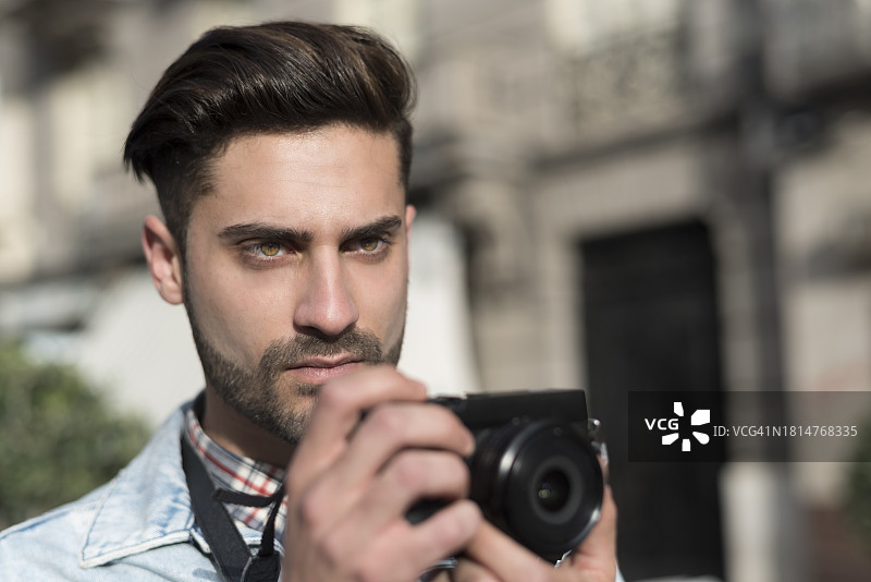 在城市中使用微单相机拍照的年轻男人图片素材