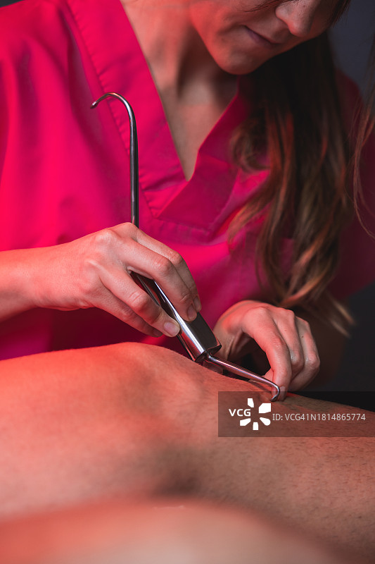 年轻理疗师在理疗中心用热灯对膝盖损伤进行治疗按摩图片素材