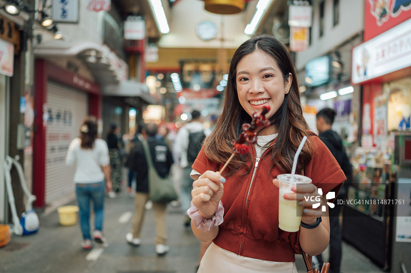 亚洲独自旅行者在黑门市场品尝腌制小章鱼图片素材