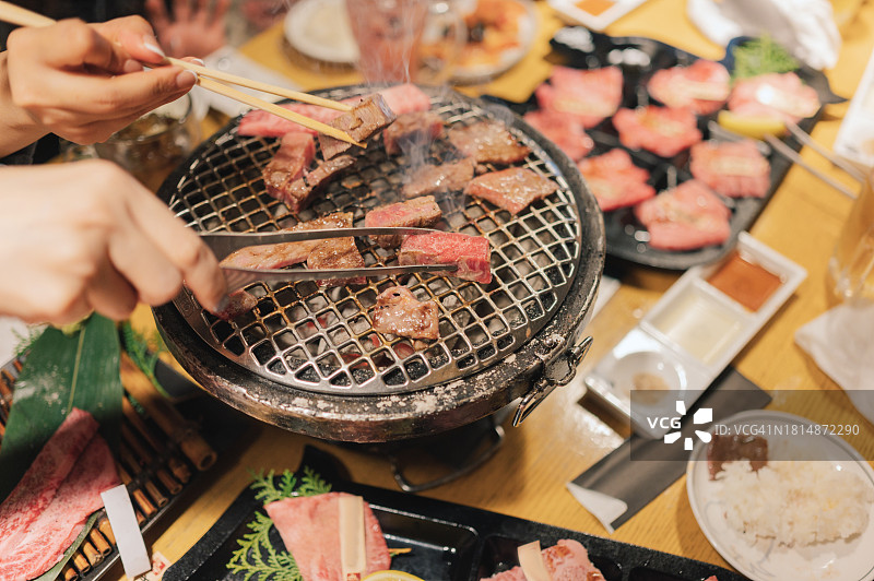 截取亚洲微笑女性手持和牛A5牛排，搭配烧烤酱和辣椒，大阪日本街头食品图片素材