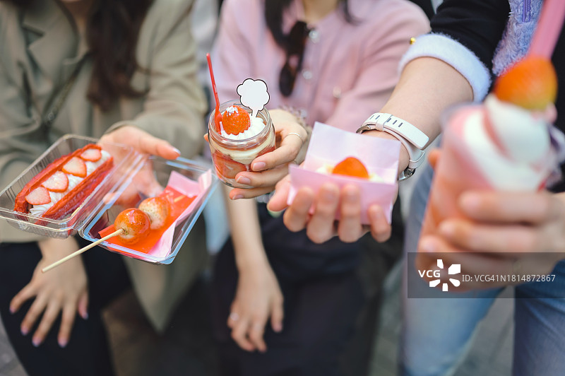 一群Z世代游客在日本道顿堀拿着红色传统大阪甜点和面包图片素材