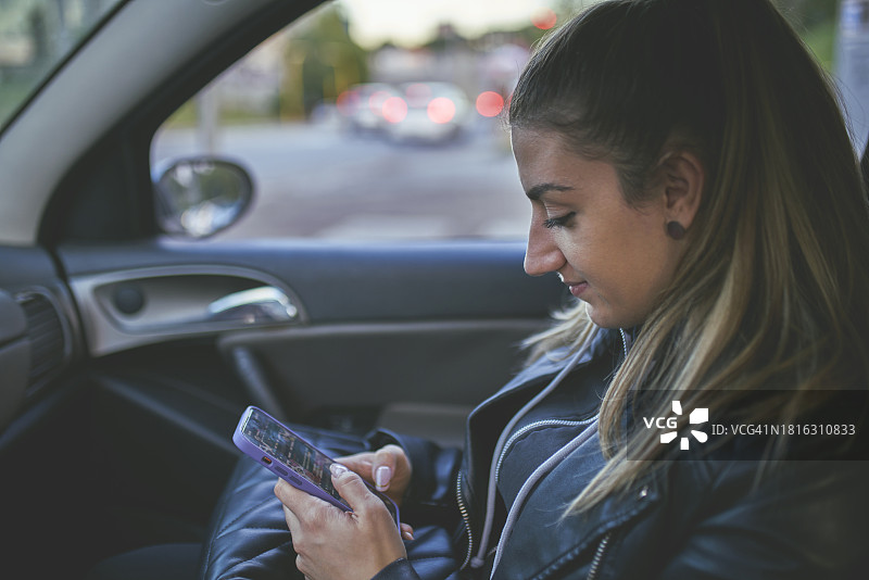 年轻女子在车内使用智能手机图片素材