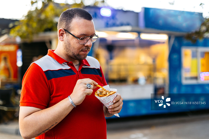 成年男子在街上吃烤肉卷饼图片素材