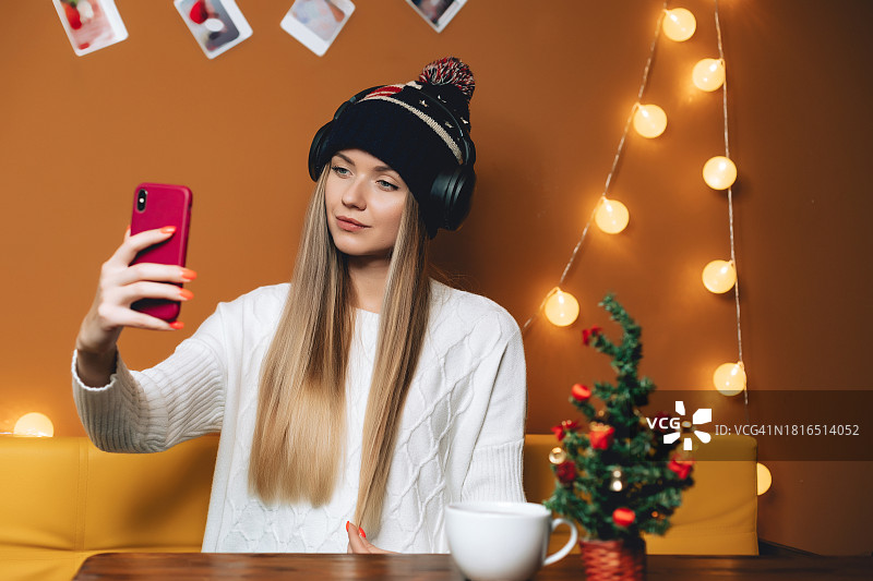 戴美国帽子和无线耳机的女性肖像（新年室内场景）图片素材