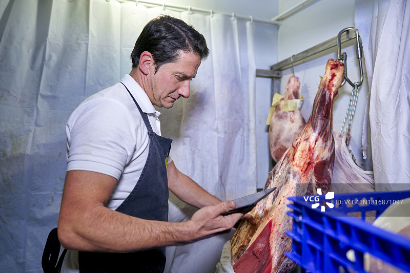 西班牙肉店的肉贩使用平板电脑管理库存和保质期图片素材