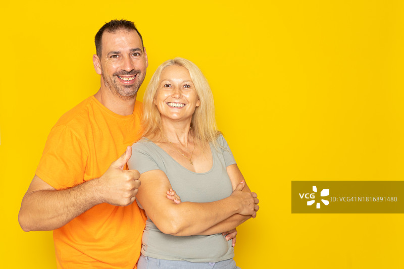 站在黄色背景前微笑的夫妇的肖像图片素材