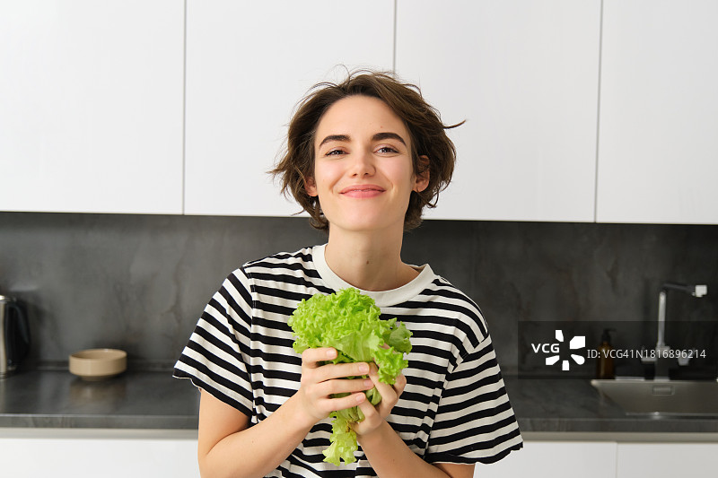 微笑的女人在家中厨房拿着蔬菜图片素材