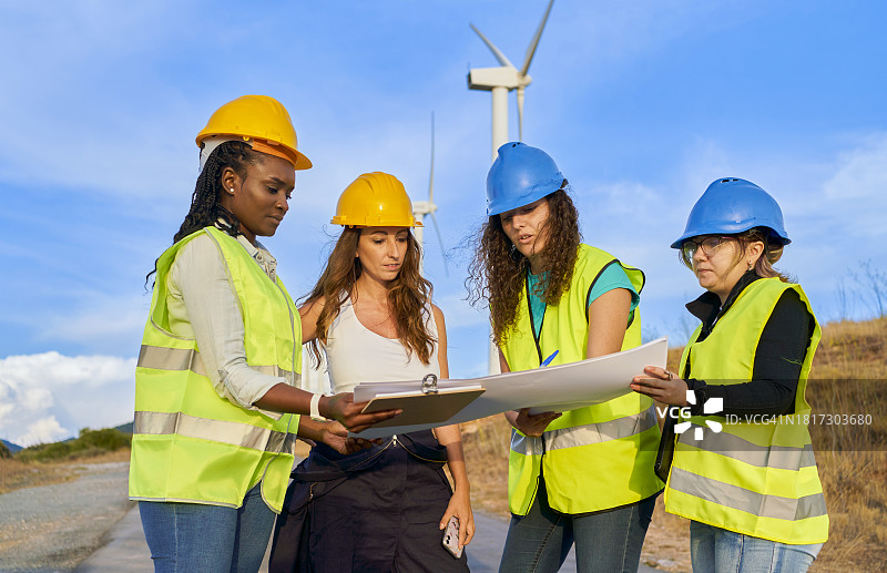 四个戴着护胸甲和头盔的女人在看建筑图纸图片素材