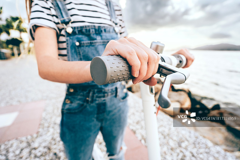 年轻女人骑着电动滑板车享受环保的海边之旅图片素材