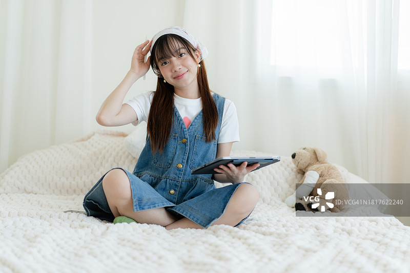 女大学生在宿舍里用平板电脑打电话图片素材