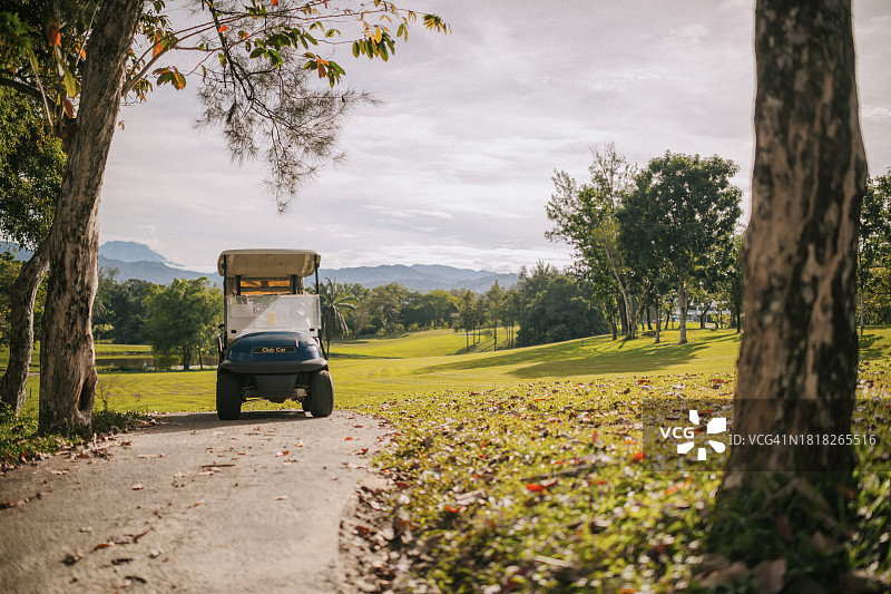 日出时分高尔夫球场上的蓝色高尔夫球车图片素材